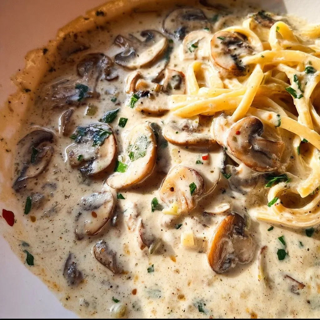 Creamy mushroom pasta sauce poured over spaghetti, garnished with herbs.