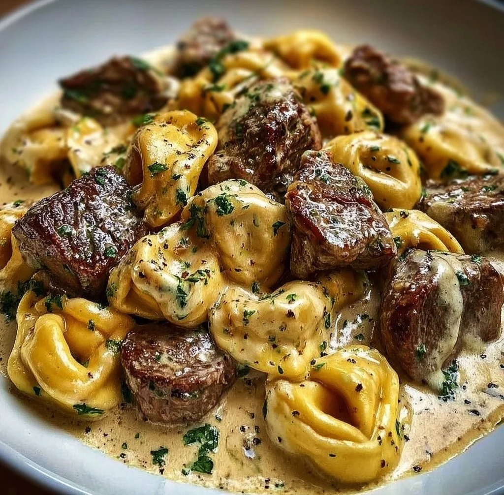 Creamy garlic steak tortellini served in a bowl with herbs
