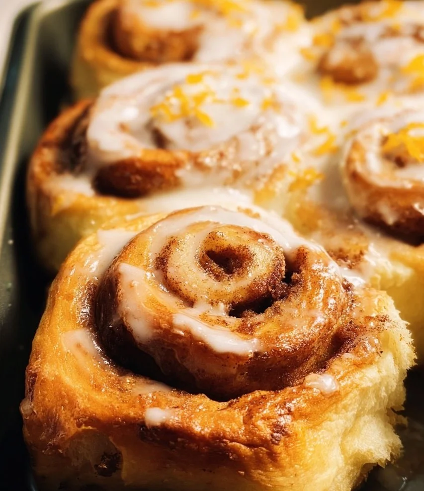 Freshly baked orange cinnamon rolls topped with creamy icing