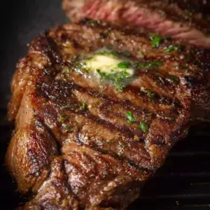 Perfectly cooked air fryer ribeye steak on a plate garnished with herbs