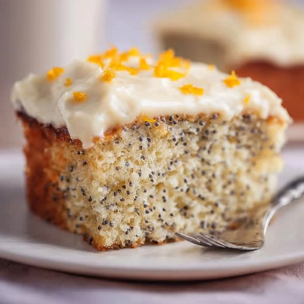 Slice of Orange Poppy Seed Cake on a plate with orange zest decoration
